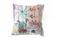 Farbenfroher Suzani-Kissenbezug mit weißem Hintergrund und großen Rosetten in Türkis, Orange und Lila mit gestickten Umrissen und dekorativer Bordüre im Boho-Vintage-Stil