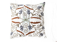 Suzani pillowcase in white with colorful embroidered loop ornaments in brown, navy, light blue and green in oriental bohemian vintage style.